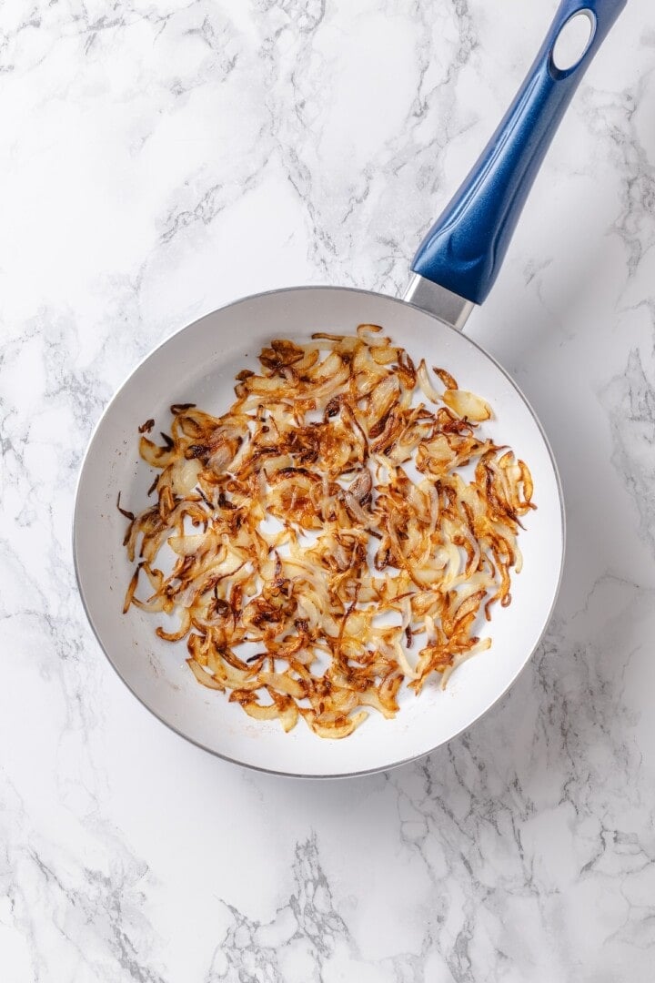 This vegan pierogi casserole layers a cheesy potato filling with lasagna noodles for pierogi vibes without the work of making dumplings! Caramelized onions in skillet.