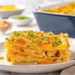 Slice of pierogi casserole on plate with green onions for garnish.