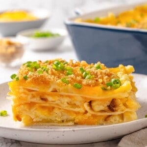 Slice of pierogi casserole on plate with green onions for garnish.