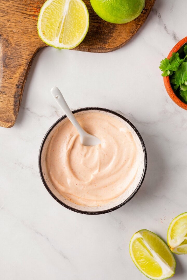 These copycat Taco Bell vegan spicy potato soft tacos are even better than the original. Crispy potatoes and creamy sauce make them so tasty! Bowl of spicy cream sauce with spoon.