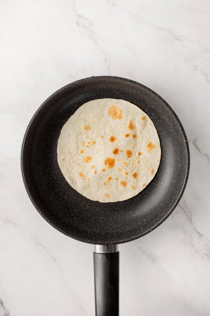 These copycat Taco Bell vegan spicy potato soft tacos are even better than the original. Crispy potatoes and creamy sauce make them so tasty! Warming flour tortilla in skillet.