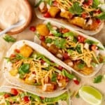 4 spicy potato soft tacos with bowl of creamy spicy sauce.