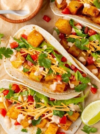 4 spicy potato soft tacos with bowl of spicy cream sauce.