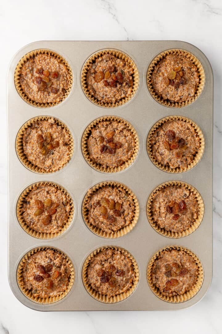 This moist vegan bran muffin recipe is made with whole wheat flour, raisins, and spiced with cinnamon for an easy, wholesome breakfast! Unbaked cinnamon raisin bran muffins in pan.