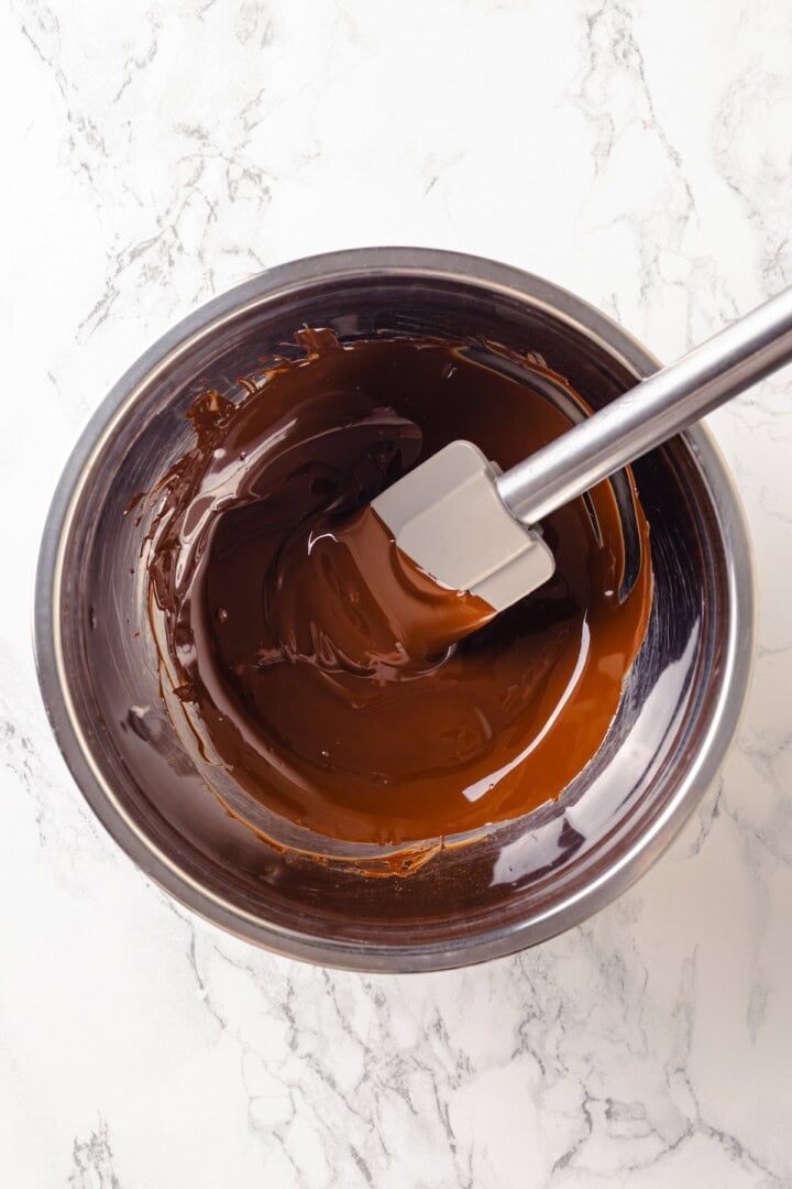 Silken Tofu Chocolate Mousse is the easiest vegan dessert you'll ever make! It's rich and indulgent, with a velvety smooth texture. So good! Bowl of melted chocolate with rubber spatula.