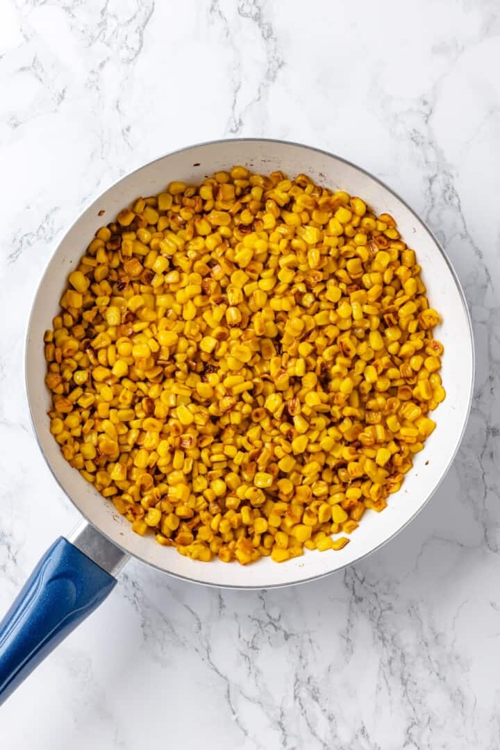 This vegan Mexican Street Corn Dip is creamy, smoky, and a little bit spicy (just like elotes!) for an easy appetizer everyone will love! Corn charring in skillet.