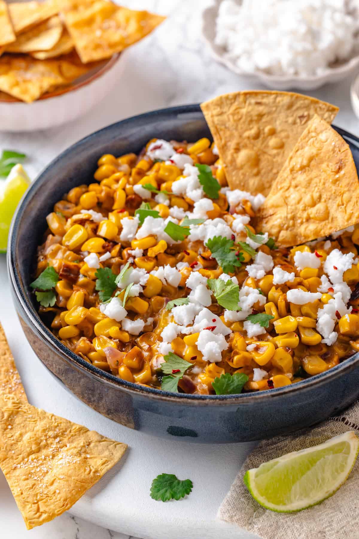 This vegan Mexican Street Corn Dip is creamy, smoky, and a little bit spicy (just like elotes!) for an easy appetizer everyone will love! Bowl of Mexican street corn dip with two tortilla chips.