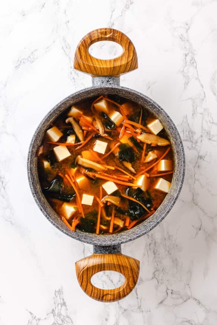 This cozy Miso Tofu Soup recipe is made with wakame, ginger, carrots and homemade dashi for a light, nourishing and flavorful vegan soup. Pot of miso tofu soup with carrots and wakame.