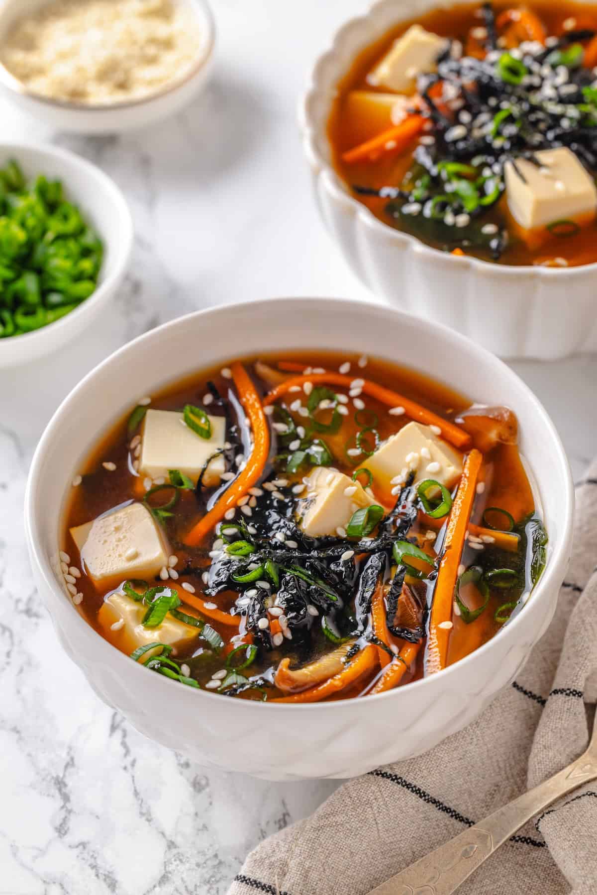 This cozy Miso Tofu Soup recipe is made with wakame, ginger, carrots and homemade dashi for a light, nourishing and flavorful vegan soup. Two bowls of miso soup with tofu.