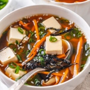 Spoonful of vegan miso tofu soup in bowl.