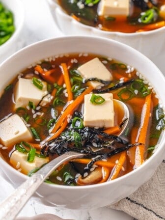 Spoonful of vegan miso tofu soup in bowl.