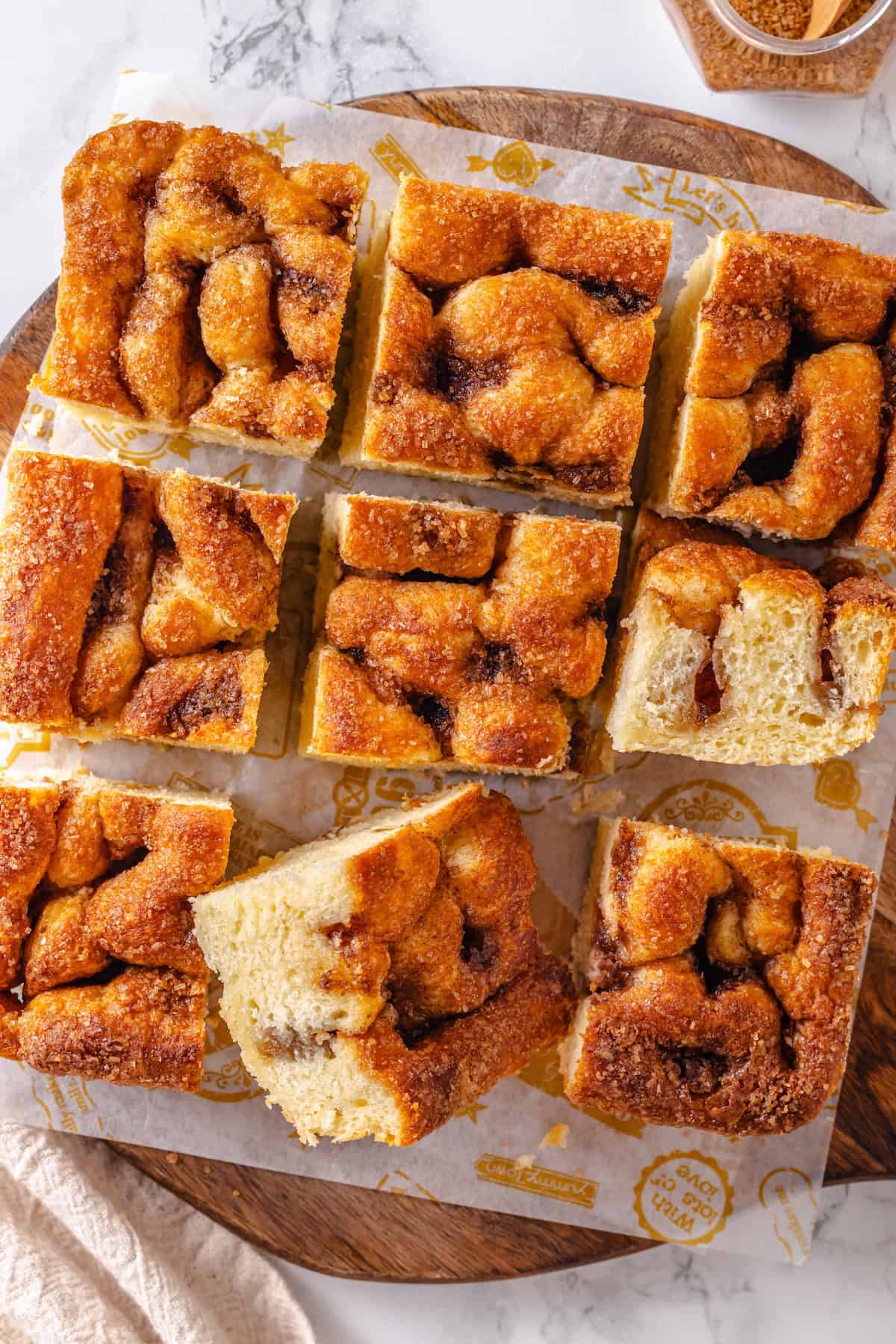 Sliced Moravian sugar cake on parchment-lined wooden board. - 13