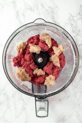 Pieces of red and white salami dough in food processor.