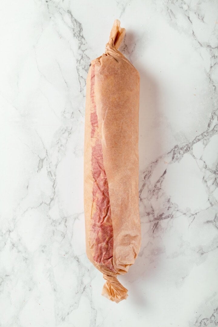 This easy vegan salami recipe is smoky, savoury and sliceable, just like the real deal! Perfect for sandwiches and charcuterie boards. Vegan salami log wrapped in parchment.