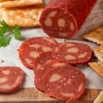 Slices of vegan salami on wooden board.