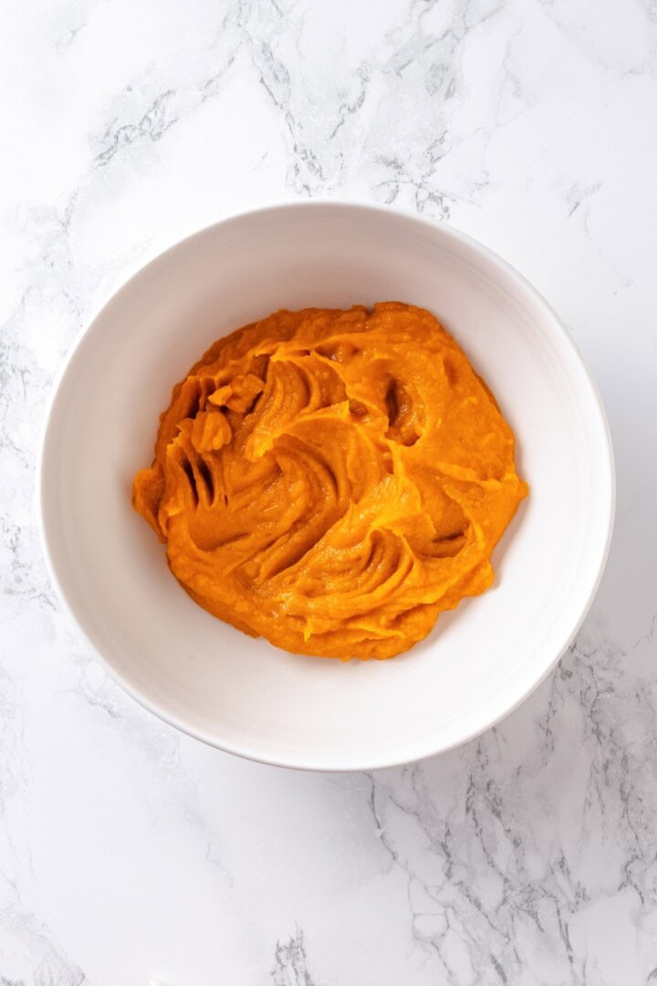 This soft, pillowy homemade sweet potato gnocchi is tossed with rosemary garlic butter and walnuts for a restaurant-style vegan dinner! Mashed sweet potato in bowl.