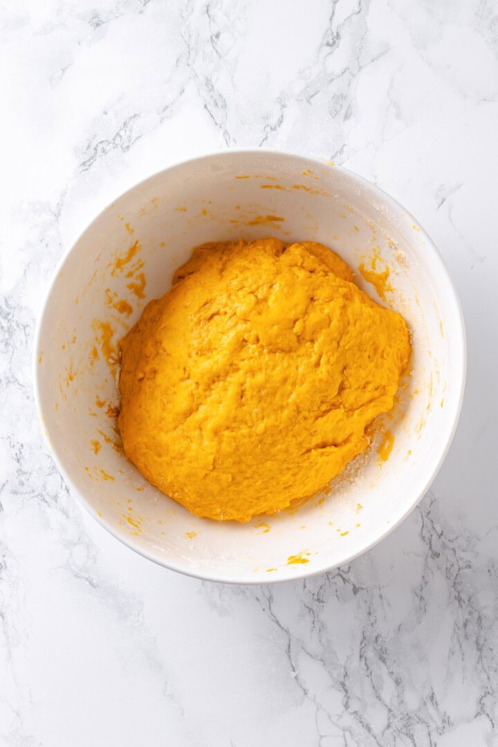 This soft, pillowy homemade sweet potato gnocchi is tossed with rosemary garlic butter and walnuts for a restaurant-style vegan dinner! Sweet potato gnocchi dough in mixing bowl.