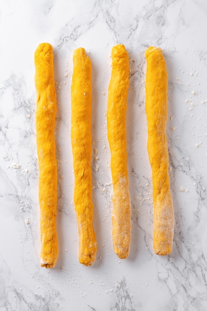 This soft, pillowy homemade sweet potato gnocchi is tossed with rosemary garlic butter and walnuts for a restaurant-style vegan dinner! Ropes of sweet potato gnocchi dough.
