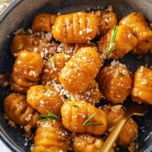 Bowl of sweet potato gnocchi with vegan parmesan and rosemary.