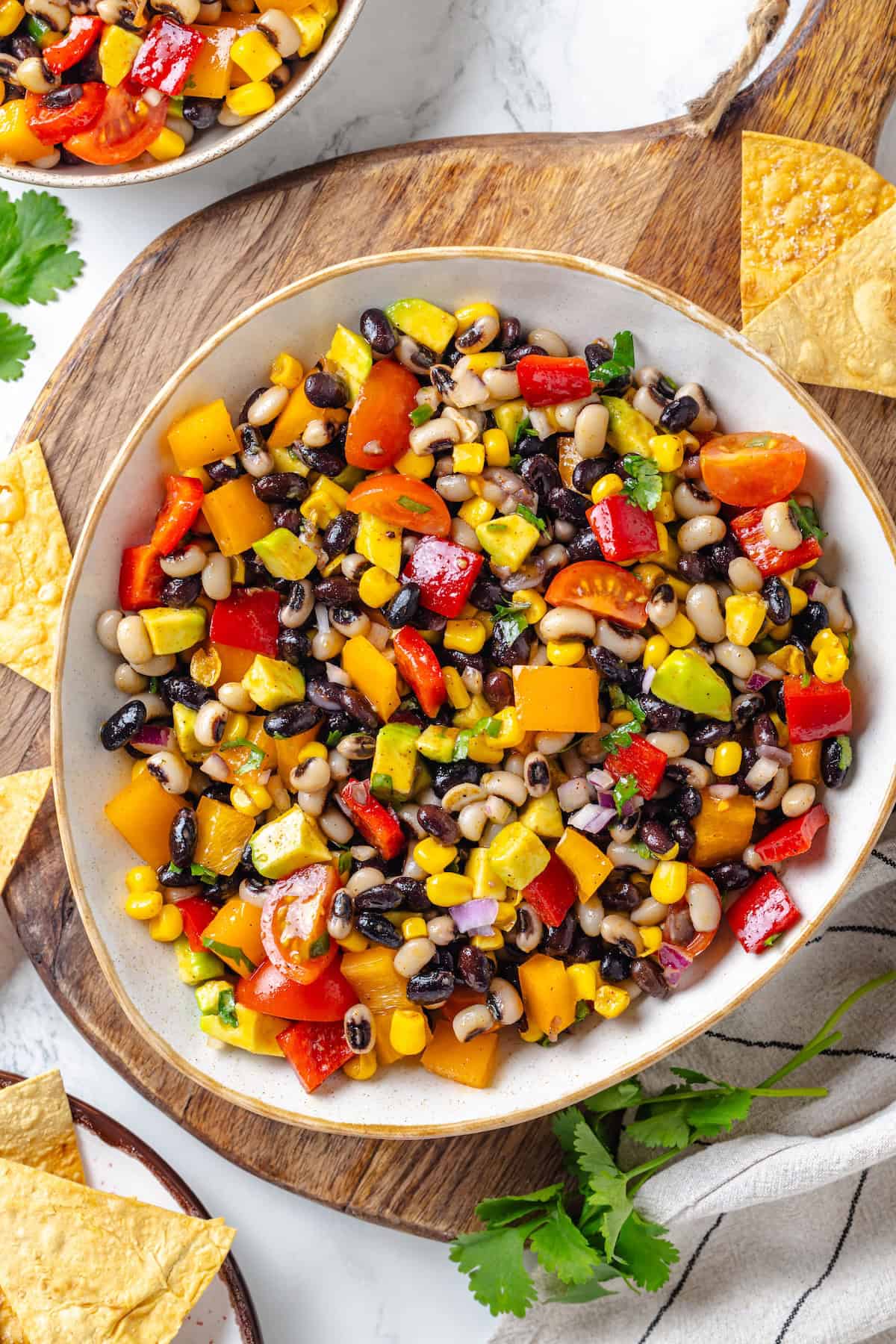 This cowboy caviar recipe is made with black-eyed peas, black beans, avocado, veggies, and a zesty dressing. Use it as a dip or a side dish! Cowboy caviar in bowl.