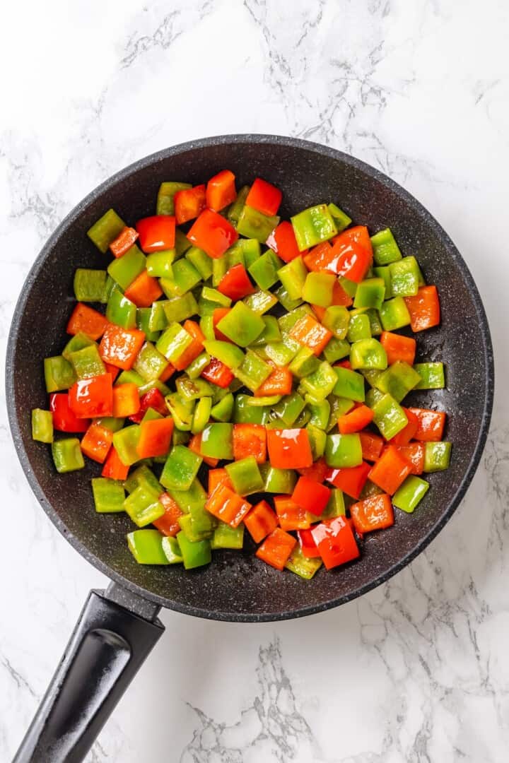 This crispy kung pao tofu is made with bell peppers, crunchy peanuts and a sweet-spicy sauce for a dinner that's even better than takeout! Stir fried red and green bell peppers in skillet.