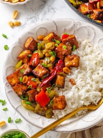 Bowl of white rice and kung pao tofu with fork.