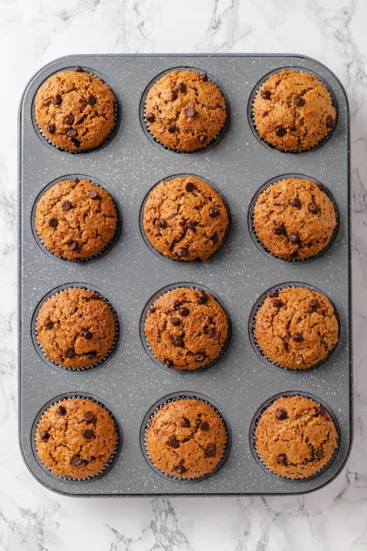 These moist peanut butter banana muffins are made with whole wheat flour and chocolate chips for a wholesome muffin that tastes like a treat! Muffin pan with peanut butter banana muffins.