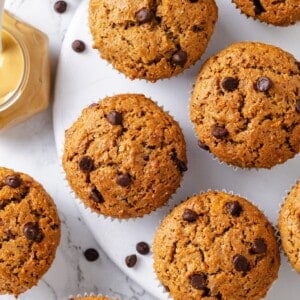 Chocolate chip peanut butter banana muffins on countertop and marble board.