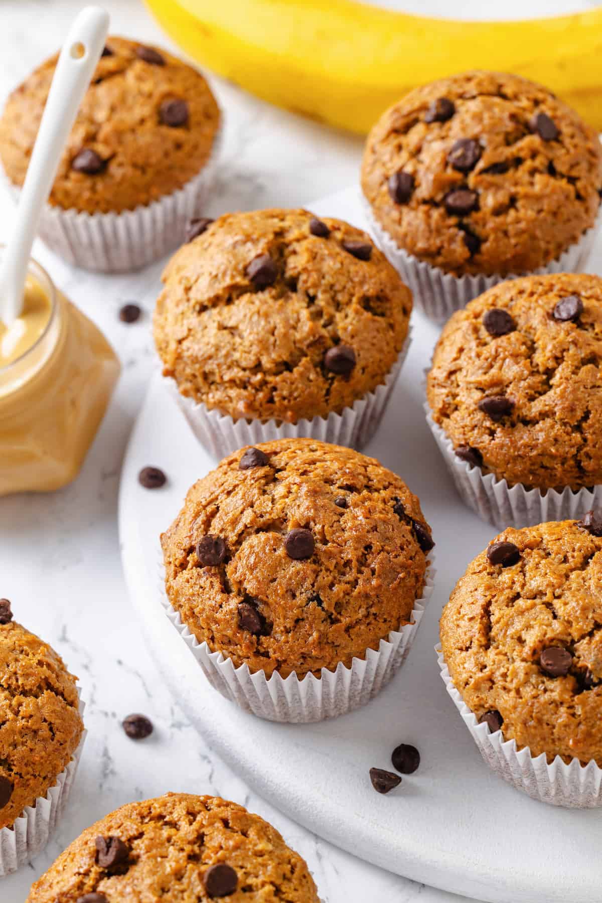 These moist peanut butter banana muffins are made with whole wheat flour and chocolate chips for a wholesome muffin that tastes like a treat! Chocolate chip peanut butter banana muffins on marble board.