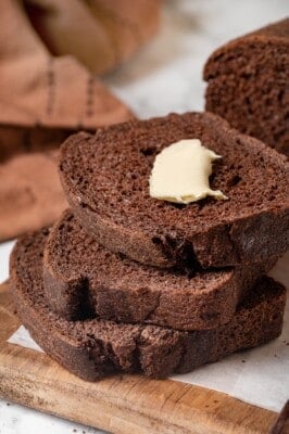 3 slices of pumpernickel bread, with butter on top slice.