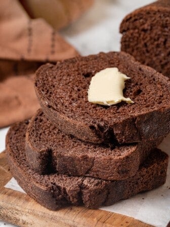 3 slices of pumpernickel bread, with butter on top slice.