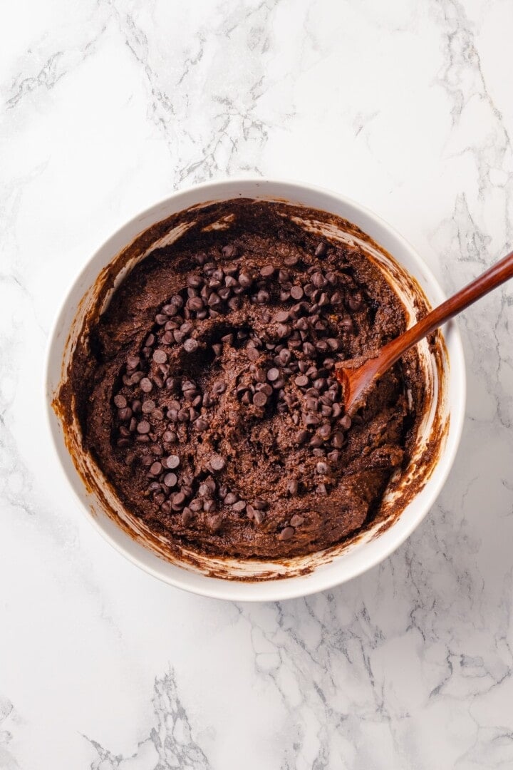 These fudgy vegan sweet potato brownies are made with maple syrup and cocoa for a treat that’s naturally sweet, gluten-free, and oh so rich! Chocolate chips added to bowl of sweet potato brownie batter.