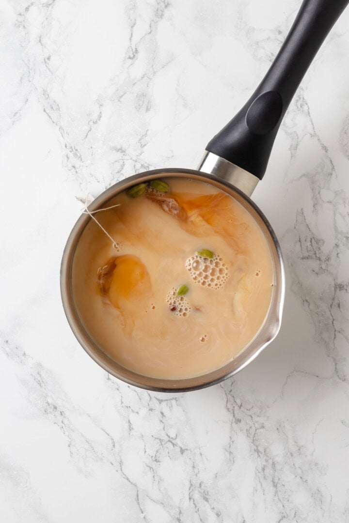 This cozy vegan spiced chai chai is creamy, warmly spiced, and easy to make at home with oat milk and whole spices. Ingredients for spiced chai in saucepan.