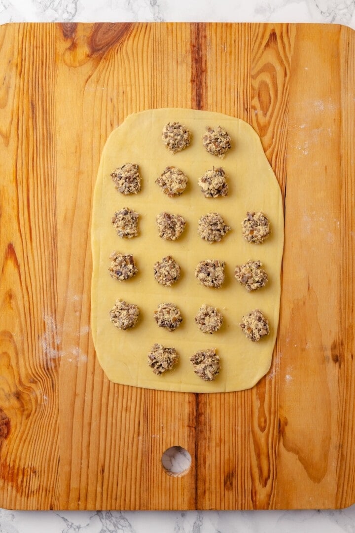 This homemade mushroom ravioli is filled with porcini, cremini and ricotta, then tossed in a creamy vegan Parmesan sauce. Restaurant-worthy! Mushroom filling added to sheet of pasta.