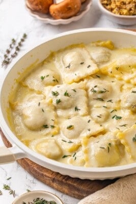 Pan of mushroom ravioli with vegan parmesan sauce and thyme.