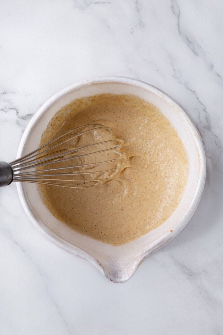 These oat flour pancakes are thick and fluffy, made with simple ingredients and they're naturally gluten-free and vegan. A game changer! Whisking oat flour pancake batter in bowl.