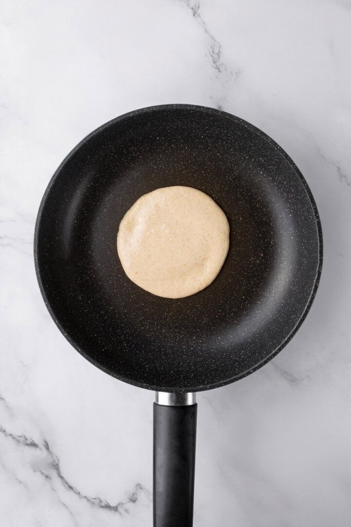 These oat flour pancakes are thick and fluffy, made with simple ingredients and they're naturally gluten-free and vegan. A game changer! Oat flour pancake in skillet before flipping