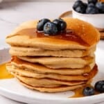 Stack of oat flour pancakes topped with blueberries and syrup.