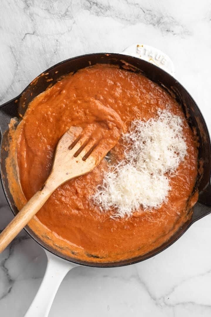 This one pot cheesy tomato gnocchi is creamy, comforting, and ready in under 30 minutes for an easy vegan weeknight dinner! Vegan cheese added to pan of tomato sauce.