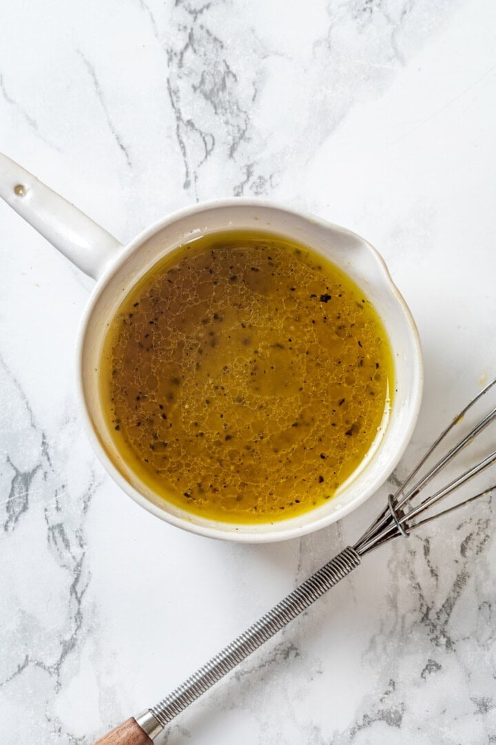 This easy pineapple cucumber salad is crisp, juicy and tossed in a tangy lime dressing. It’s refreshing, quick and perfect for summer! Lime vinaigrette in small bowl set next to whisk.