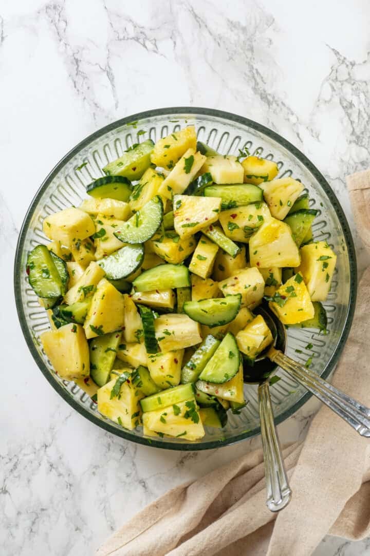 This easy pineapple cucumber salad is crisp, juicy and tossed in a tangy lime dressing. It’s refreshing, quick and perfect for summer! Pineapple cucumber salad in mixing bowl.