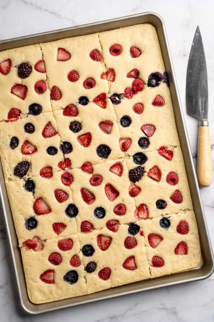 These fluffy sheet pan pancakes bake in one pan for an easy, no-flip breakfast that’s perfect for busy mornings or brunch. Sliced pancakes in sheet pan with berries.