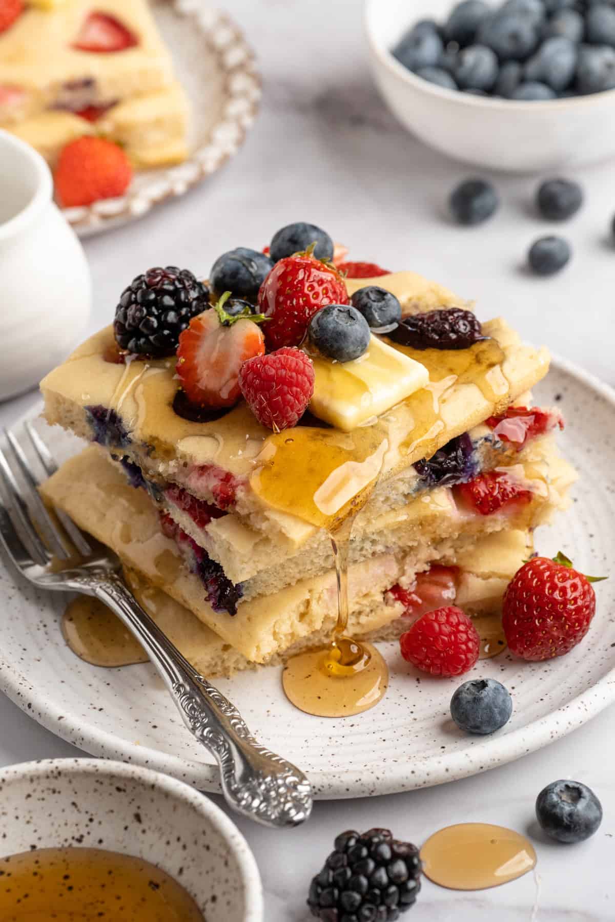 These fluffy sheet pan pancakes bake in one pan for an easy, no-flip breakfast that’s perfect for busy mornings or brunch. Stack of sheet pan pancakes with fresh berries and maple syrup.