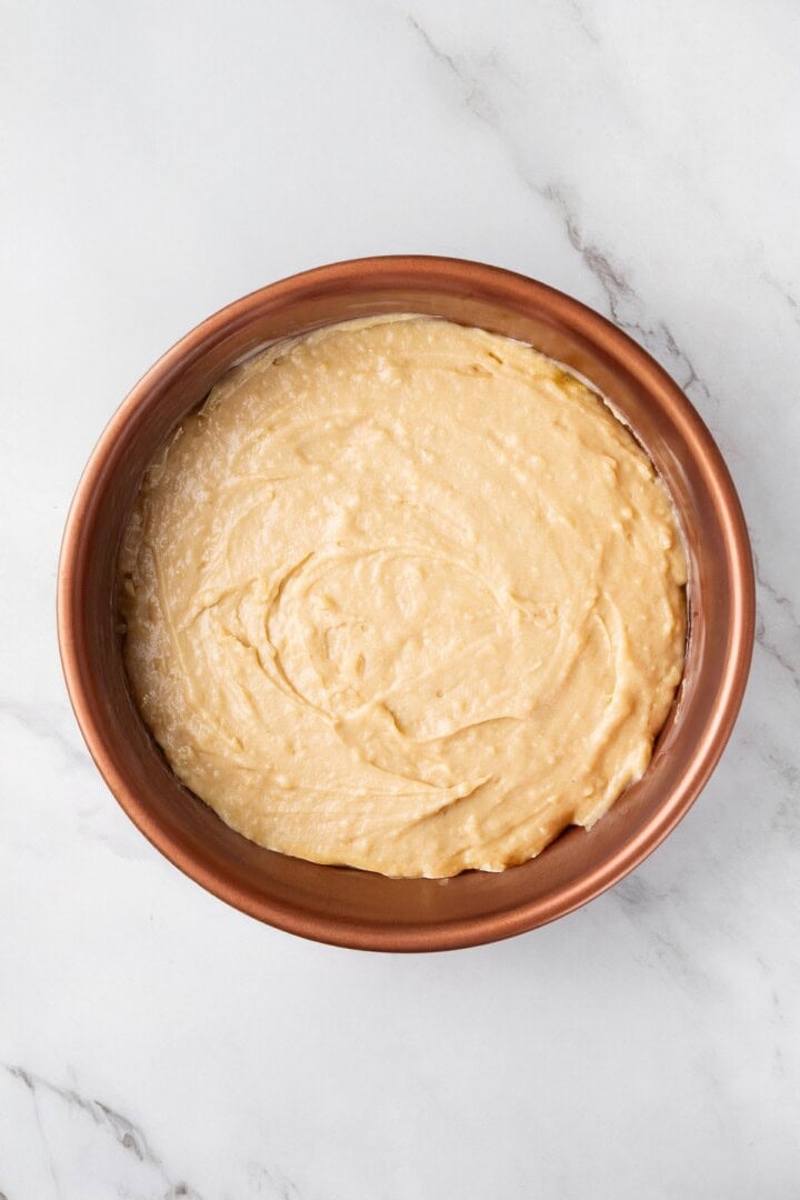 This easy upside down apple cake features tender, spiced cake topped with sticky caramel apples. It’s cozy, simple and perfect for fall! Batter for upside down apple cake spread in pan.