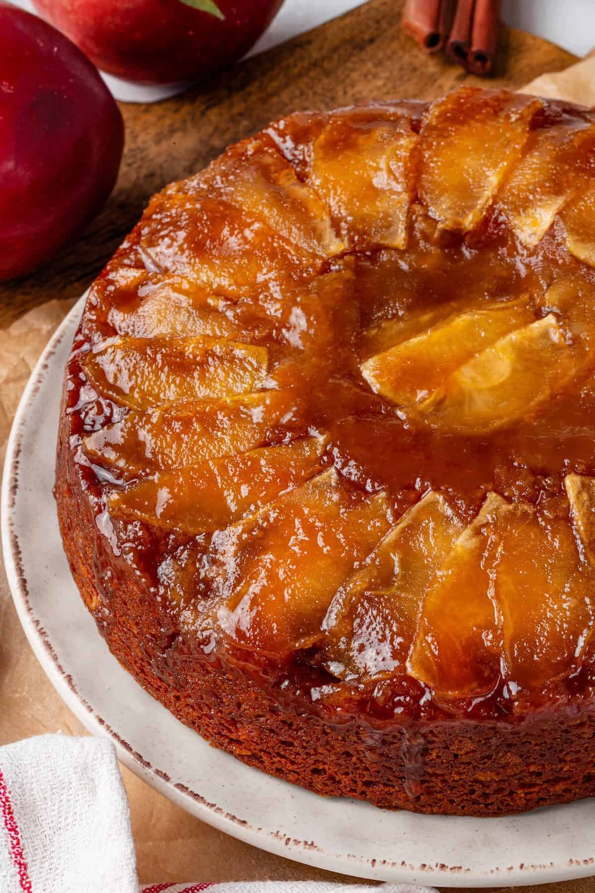 This easy upside down apple cake features tender, spiced cake topped with sticky caramel apples. It’s cozy, simple and perfect for fall! Vegan upside down apple cake on serving plate.
