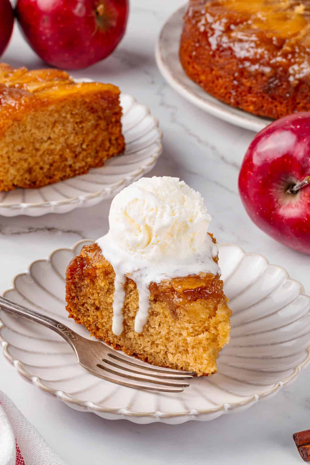 This easy upside down apple cake features tender, spiced cake topped with sticky caramel apples. It’s cozy, simple and perfect for fall! Slice of upside down apple cake topped with ice cream.