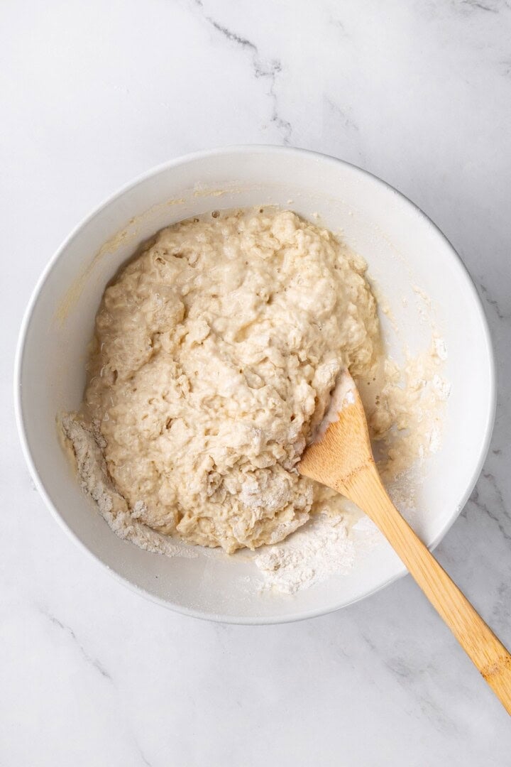 This easy beer bread recipe is soft, moist and baked with a crisp golden crust. It’s a simple no-knead loaf ready to eat in under an hour! Wooden spoon stirring batter for beer bread.