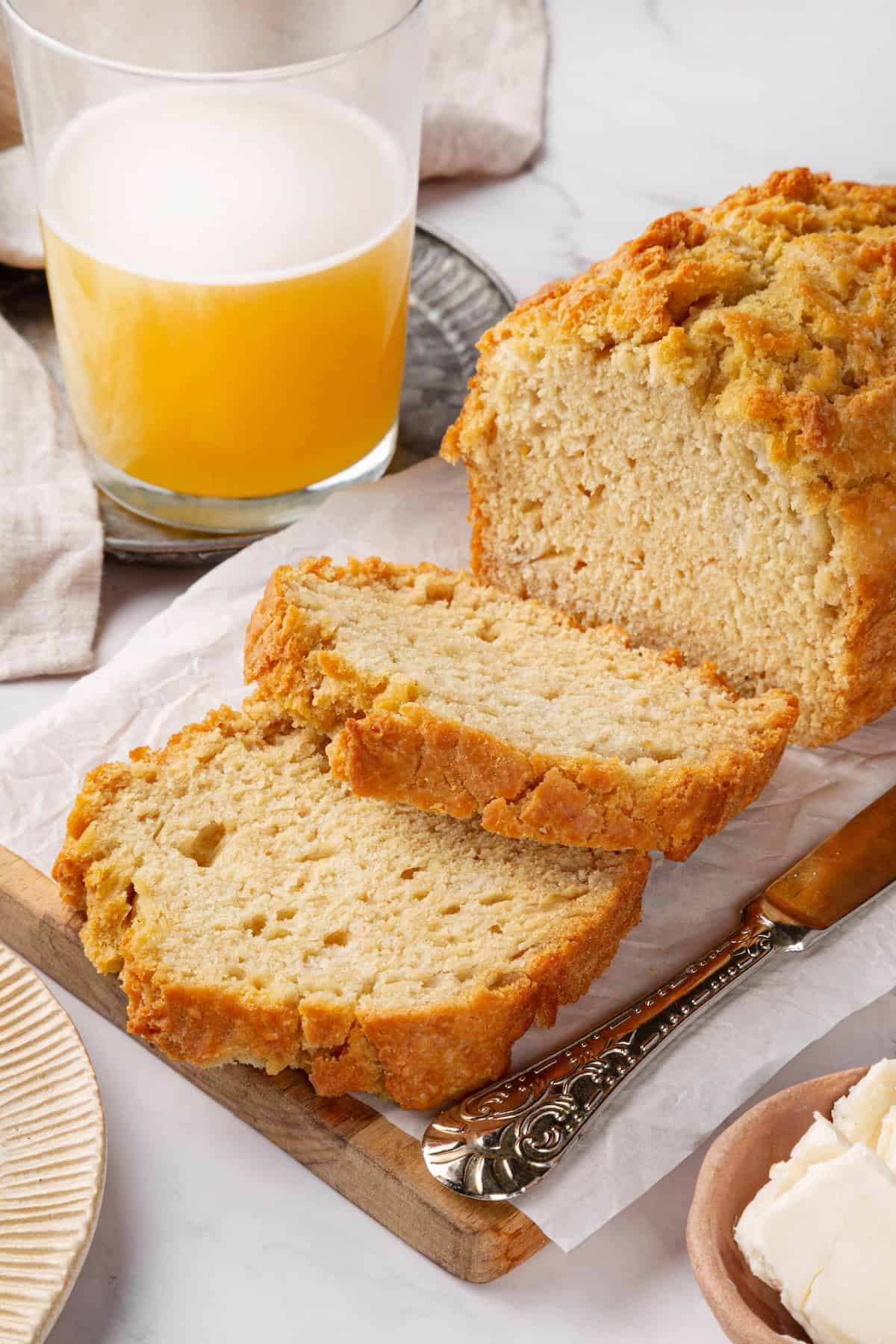 This easy beer bread recipe is soft, moist and baked with a crisp golden crust. It’s a simple no-knead loaf ready to eat in under an hour! Two slices cut from loaf of vegan beer bread.
