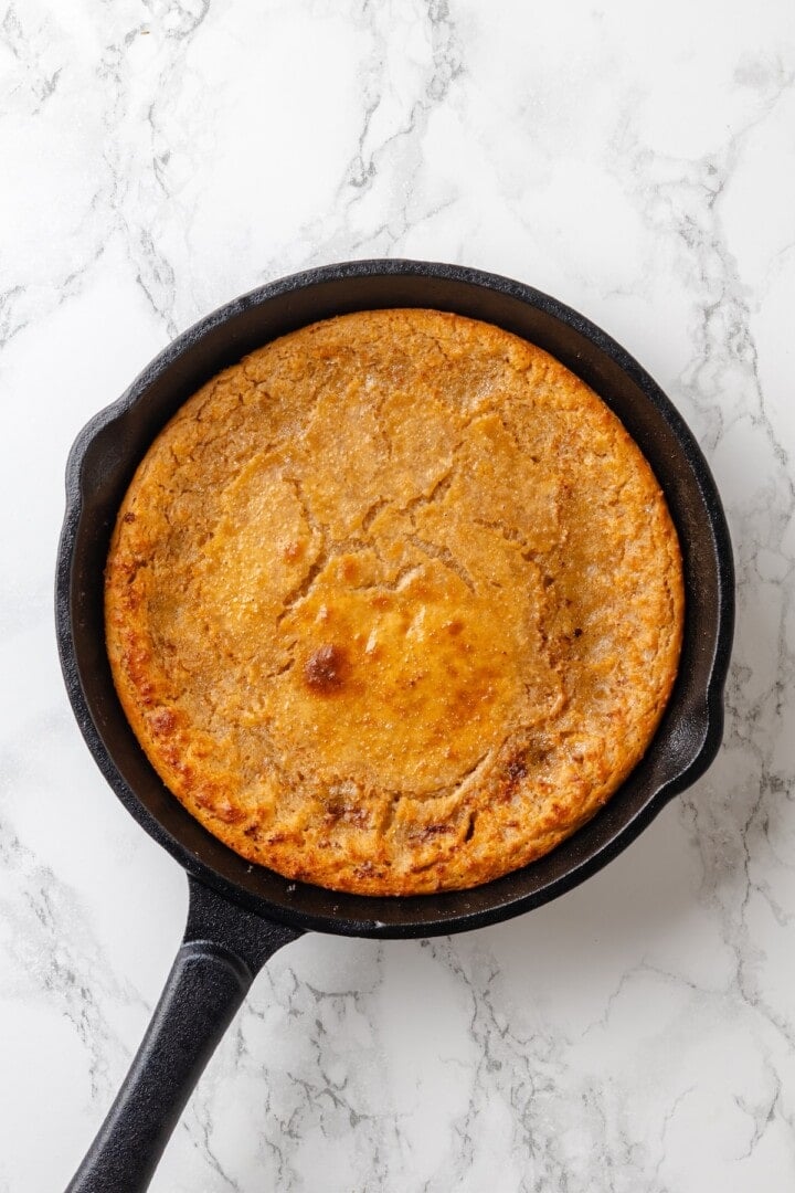 German pancakes bake up puffy and golden with crisp edges and a tender middle. Aquafaba stands in for the eggs in this easy vegan recipe! German pancake in cast iron skillet.