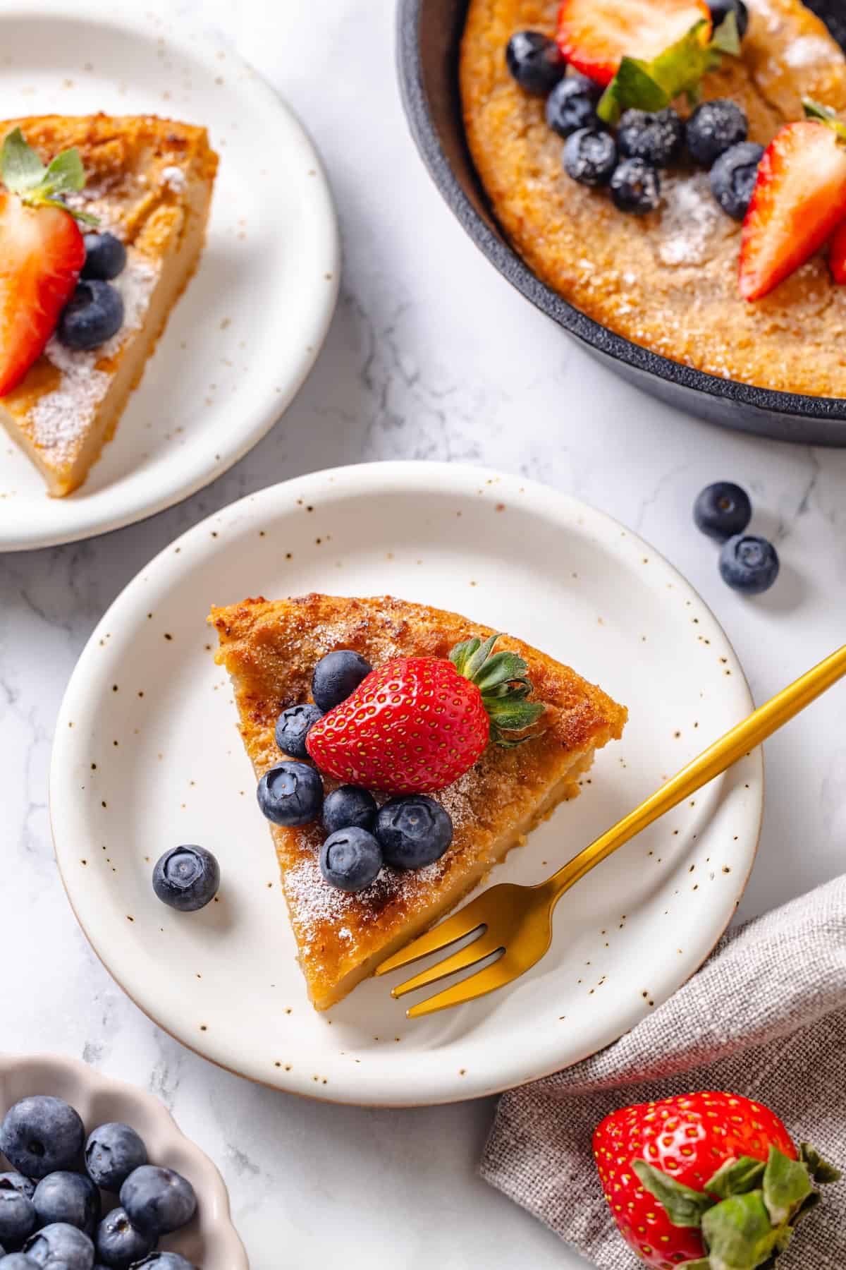 German pancakes bake up puffy and golden with crisp edges and a tender middle. Aquafaba stands in for the eggs in this easy vegan recipe! German pancake slices on two plates next to pan.